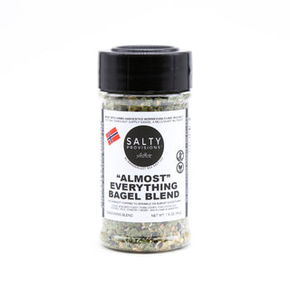 A shaker bottle of 'ALMOST' Everything Bagel Sea Salt Blend with visible sesame seeds, onion, and herbs inside. Made by Salty Provisions.