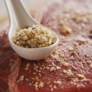 This is a picture of uncooked steak sprinkled with the Roasted Garlic Sea Salt from Salty Provisions. 